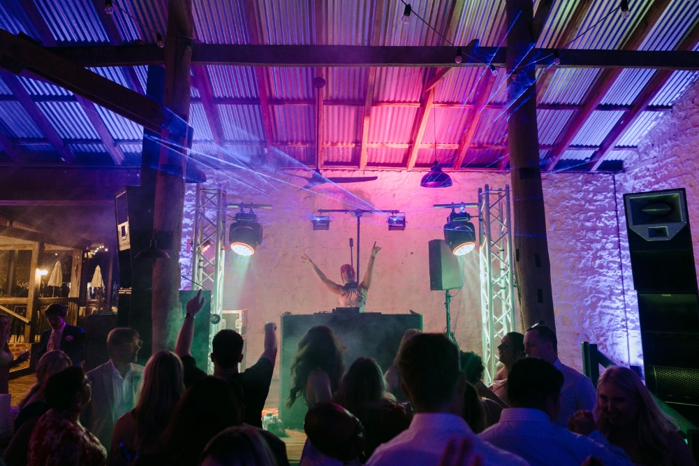 DJ with arms raised at a wedding with Funktion One speakers set up